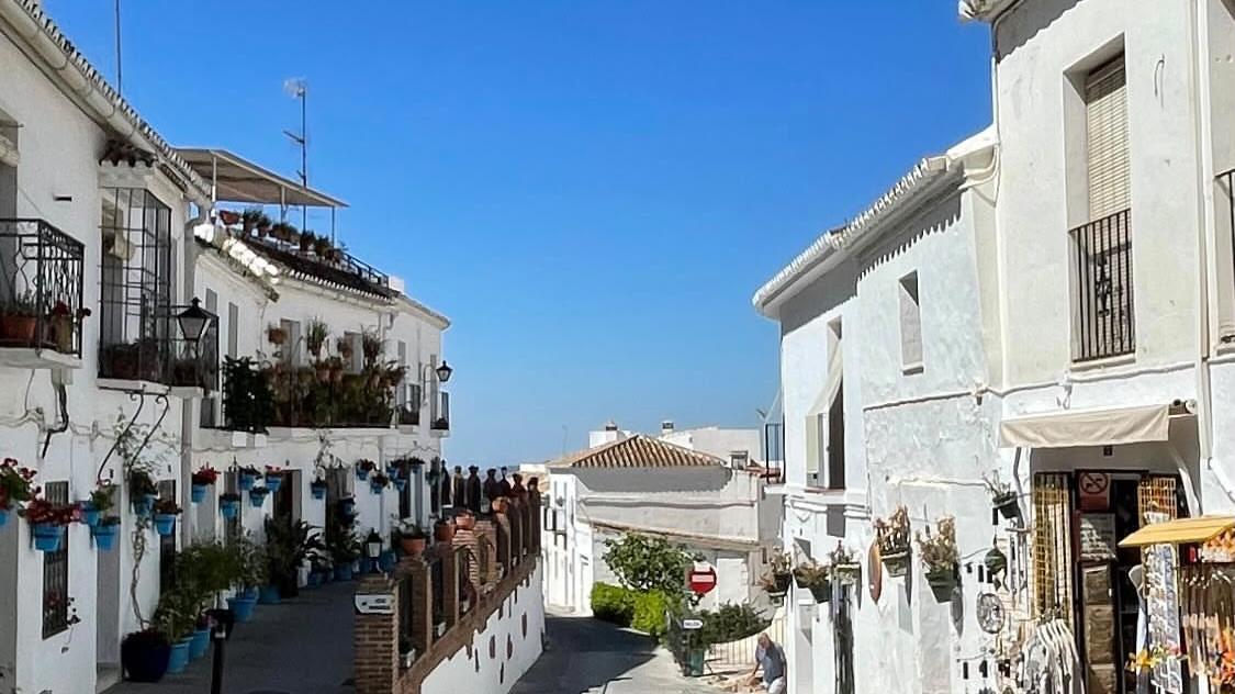 Wit Andalusisch dorpsstraatje met bloempotten tegen de gevels